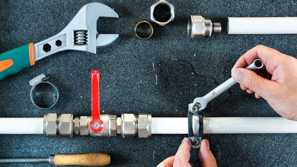 Plumber repairing a pipe valve with an adjustable wrench in Leesburg