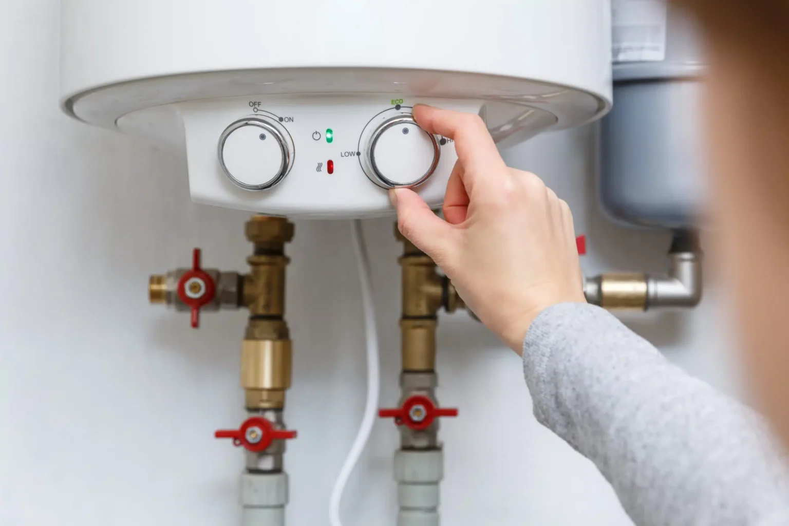 Homeowner adjusting the temperature controls on a water heater in Leesburg